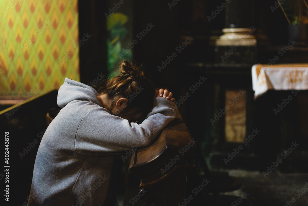 Woman praying on her knees in an ancient Catholic temple to God. Hands folded in prayer concept for faith, spirituality and religion. Peace, hope, dreams concept Woman praying on her knees in an ancient Catholic temple to God. Hands folded in prayer concept for faith, spirituality and religion. Peace, hope, dreams concept