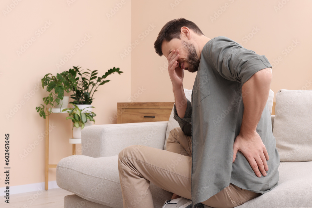 Man suffering from pain in his back at home, space for text. Arthritis symptoms Man suffering from pain in his back at home, space for text. Arthritis symptoms