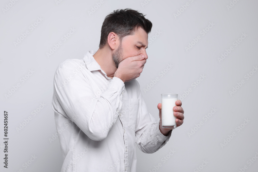 Man with glass of milk suffering from lactose intolerance on white background Man with glass of milk suffering from lactose intolerance on white background