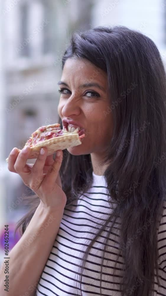 Woman eating pizza and smiling at camera Woman eating pizza and smiling at camera