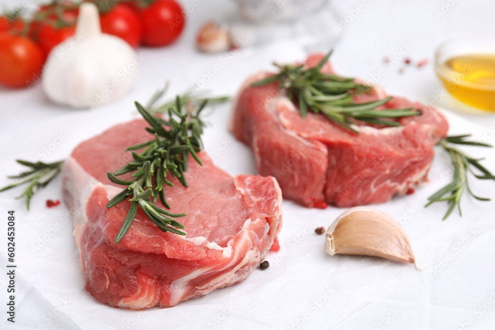 Fresh raw meat with rosemary and spices on parchment paper, closeup