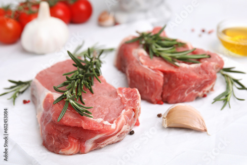 Fresh raw meat with rosemary and spices on parchment paper, closeup