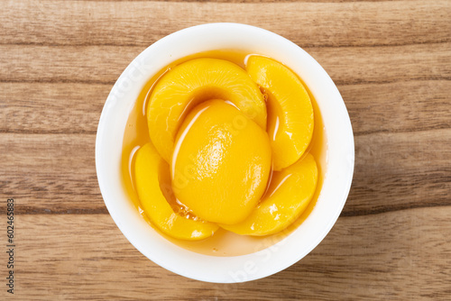 top view bowl of yellow peach syrup on wood background photo