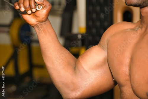 A strong African bodybuilder is intensely working out in the gym, sweating, and building chest muscles to achieve a healthy lifestyle.