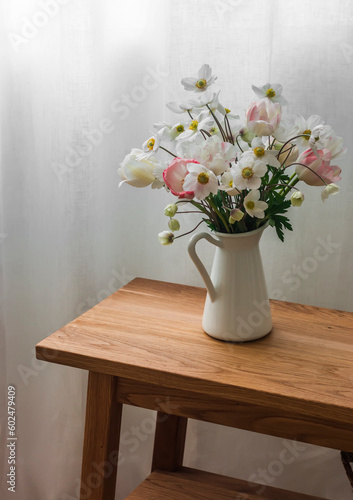 Bouquet of summer flowers in an enameled jug on an oak bench