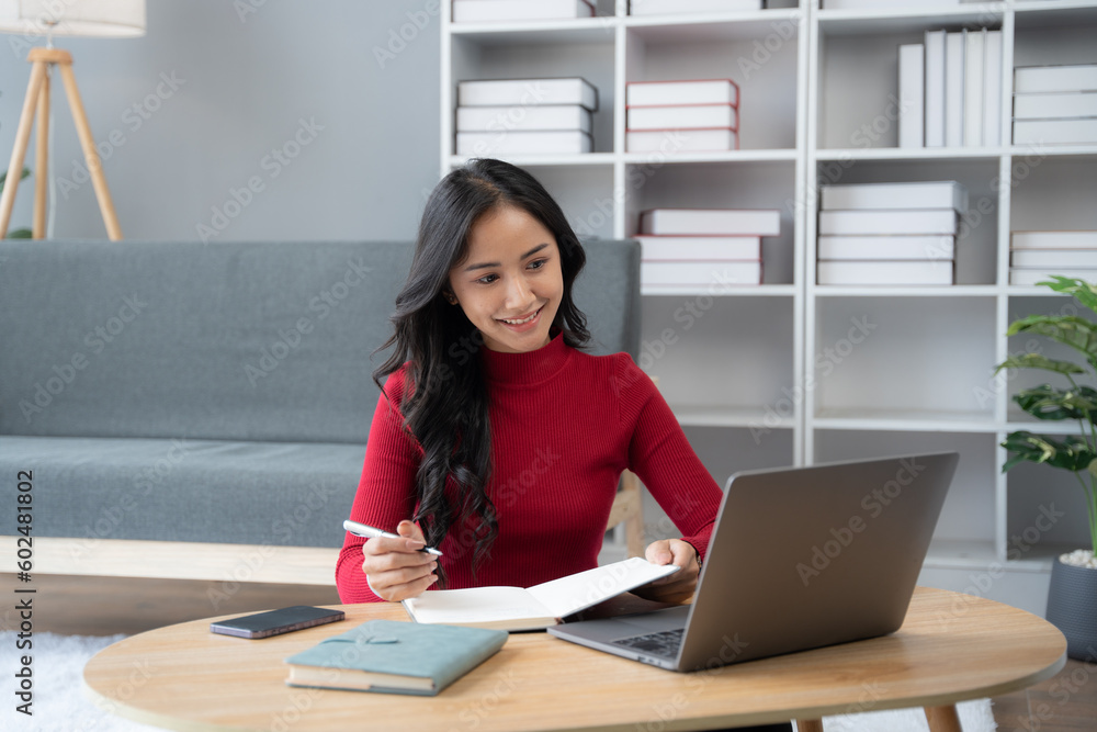 beautiful Asian girl wearing red sweater working with laptop computer in the living room. beautiful Asian girl wearing red sweater working with laptop computer in the living room.