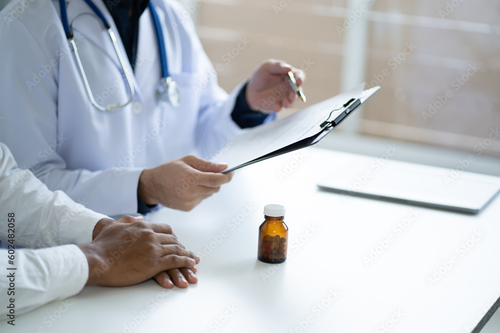 A male doctor explains the use of medicine to a sick elderly woman in the clinic office. A male doctor explains the use of medicine to a sick elderly woman in the clinic office.
