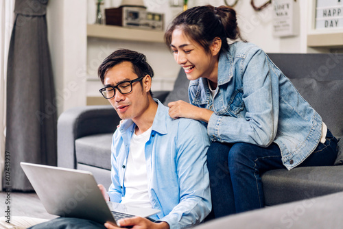 Young asian couple relaxing using laptop computer work and video conference meeting online chat.Creative business couple planning strategy analysis and brainstorm at home