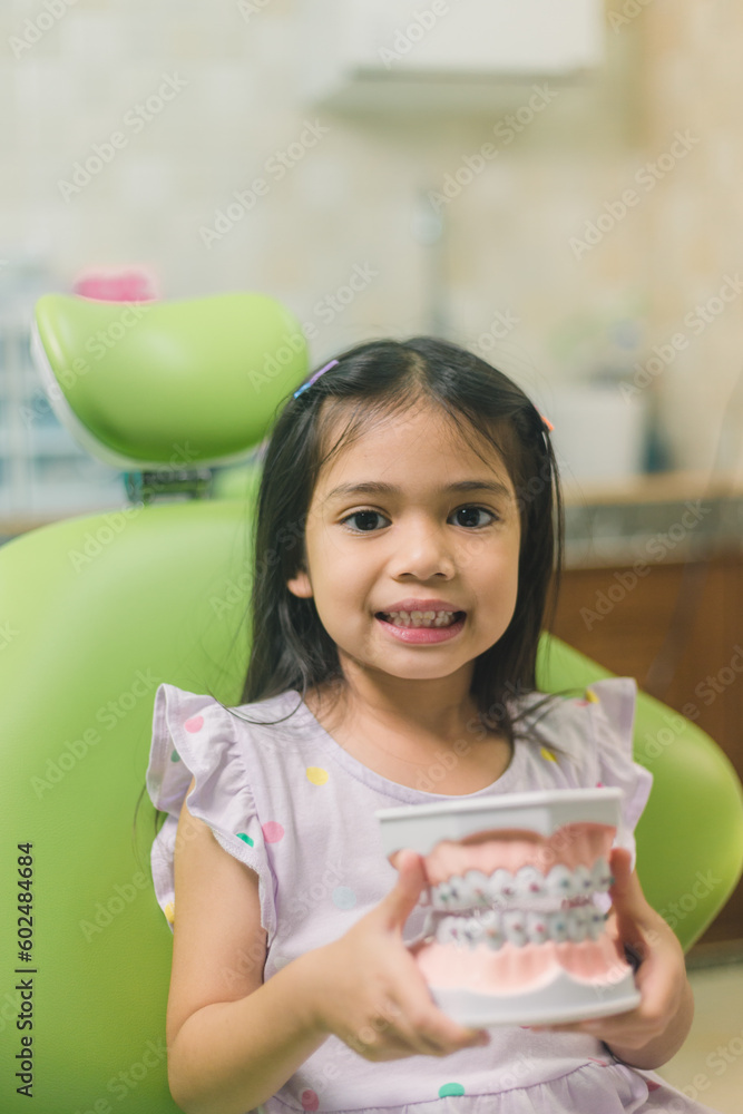 Asian girl in dental chair, with tooth brush. Medicine, dentistry and healthcare concept