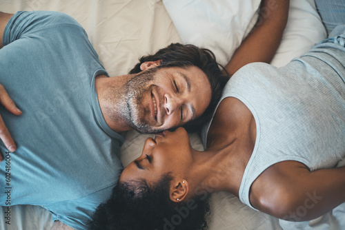 Obraz na plátne Interracial couple, kiss and relax on bed above for morning bonding, intimate relationship or love at home