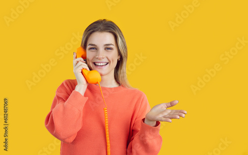Portrait of smiling millennial girl isolated on yellow background look at camera talk on corded phone. Happy young woman have pleasant conversation or call on landline telephone. Communication. photo