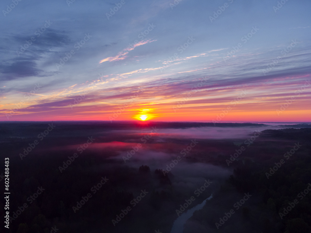 Drone's Eye View: Serene Sunrise Over Misty River and Woodland Landscape in Northern Europe