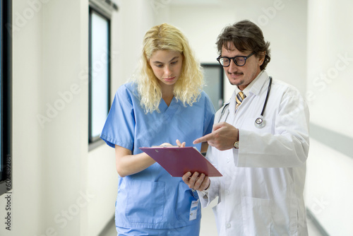 Senior caucasian doctor having discussion in a hospital hallway with nurse. Team of doctors working together on patients file at hospital. Medical staff analyzing report and working at clinic.
