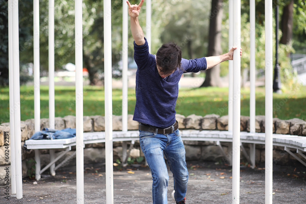 Obraz premium A young man walks in the park at lunch time. A man is on a walk in the city. A student in the park.