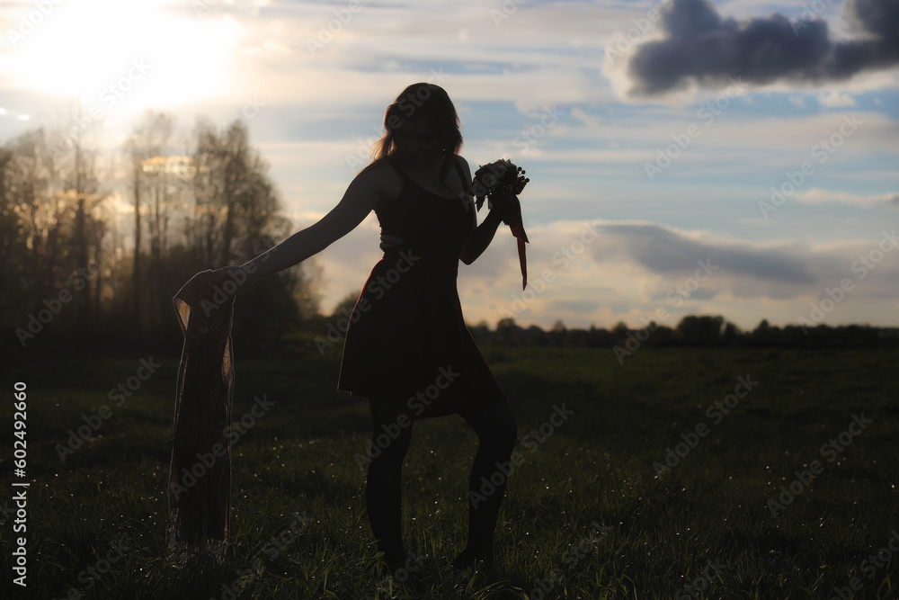 A girl in a hat on a walk in the park. A girl with a basket walks in the spring. A girl is walking along the road at sunset.