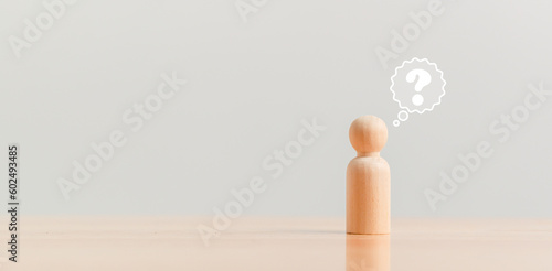 Wooden figurine as person who have questions and need help solving the problems. Man has no idea on wood table. Business marketing and Creative solution concept. photo