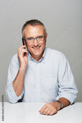 Senior businessman, phone call and studio portrait with happiness, smile and listen by gray background. Elderly man, happy and excited face for contact, chat and smartphone for networking by backdrop