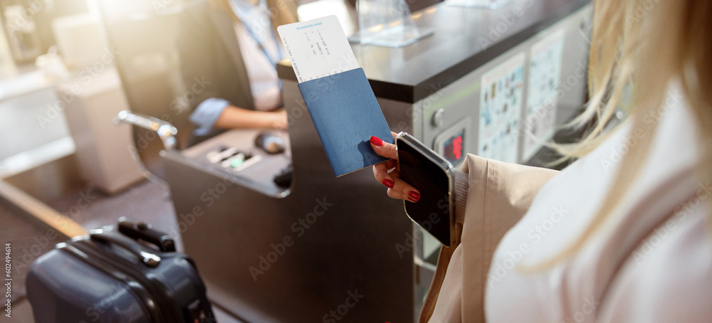Woman holding passport and tickets near reception desk Woman holding passport and tickets near reception desk