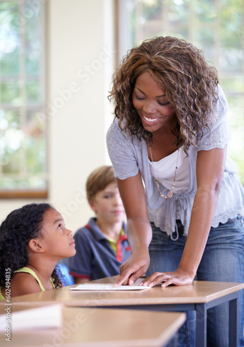 School, classroom teacher and child with education, support and language helping or check learning development. Class test, knowledge and paper assessment with african person teaching girl at desk