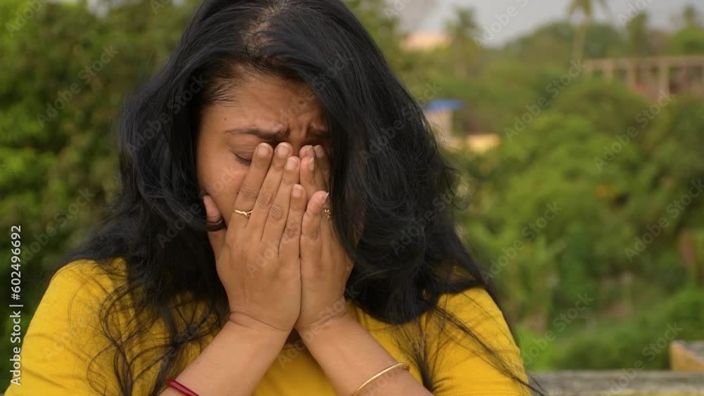 An young Indian woman caring covering her face. An young Indian woman caring covering her face.