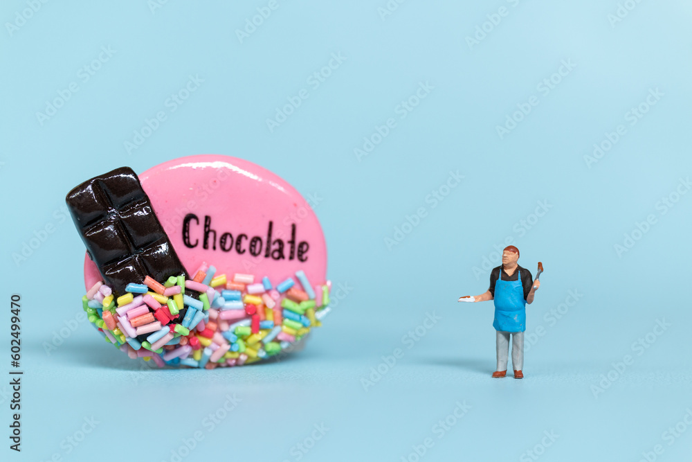 Miniature Chef with chocolate cookie on a blue  background. World Chocolate Day Concept