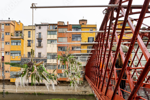 Girona, España - 13 de mayo de 2023: TEMPS DE FLORS - Flower Time. Vista del Puente Eiffel y las coloridas casas del río Onyar con decoración floral en un día lluvioso. photo