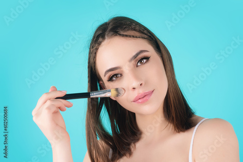 Beautiful young woman apply powder on face. Beauty Makeup. Portrait of female model with cosmetic brush. Perfect soft skin and natural makeup. Applying powder blush highlighter, foundation tone.