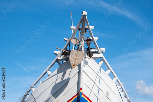 the front side of a large fishing boat moored in the harbor. anchor hanging, seen from below