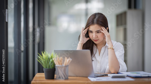 Portrait of tired young business Asian woman work with documents tax laptop computer in office. Sad, unhappy, Worried, Depression, or employee life stress concept 