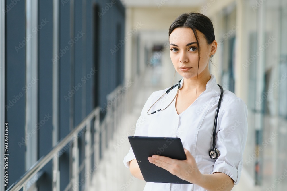 Portrait of young female doctor standing in hospital corridor. Caucasian woman working in nursing home. Portrait of young female doctor standing in hospital corridor. Caucasian woman working in nursing home.