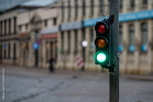 view of city traffic with traffic lights, in the foreground a semaphore with a green light, closeup