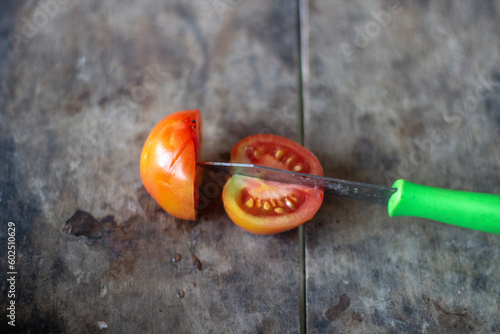 a man cut a tomato and make two tomato
