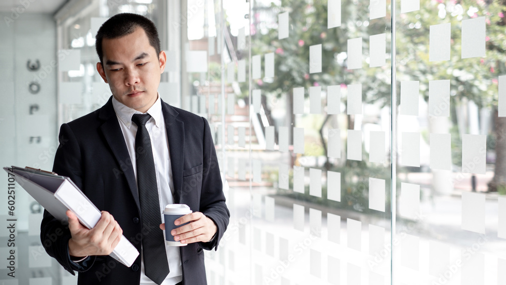 Fototapeta premium Handsome job applicant is standing in the office and holding portfolio waiting for job interview.