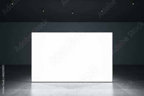 Fototapeta Naklejka Na Ścianę i Meble -  Front view of blank white glowing digital screen in dark hall interior with concrete floor and black wall. Presentation concept. Mockup, closeup, 3D Rendering
