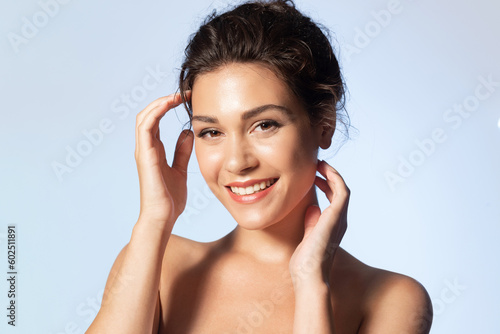 Fotografie Smiling girl touching perfect smooth glowing face skin, looking at camera