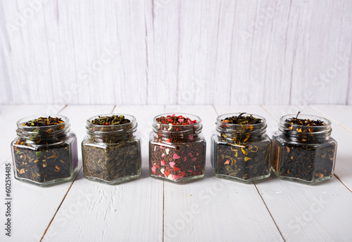 Tea of different varieties in glass jars on a white background