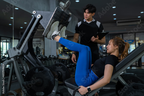 Smiling young woman and personal trainer with clipboard writing exercise plan in gym, fitness, sport, workout and diet concept