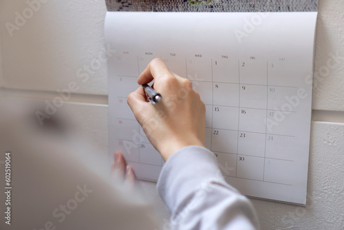 The woman writing schedule on calendar.  カレンダーに予定を書く女性