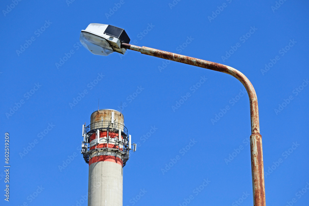 street-light-with-a-smoke-stack-and-antennas-in-the-background