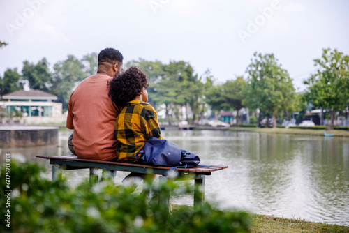 Father and daughter looking at pond sitting on bench photo