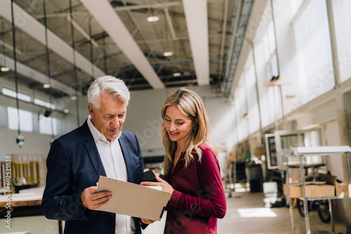Businessman discussing with colleague over documents in factory