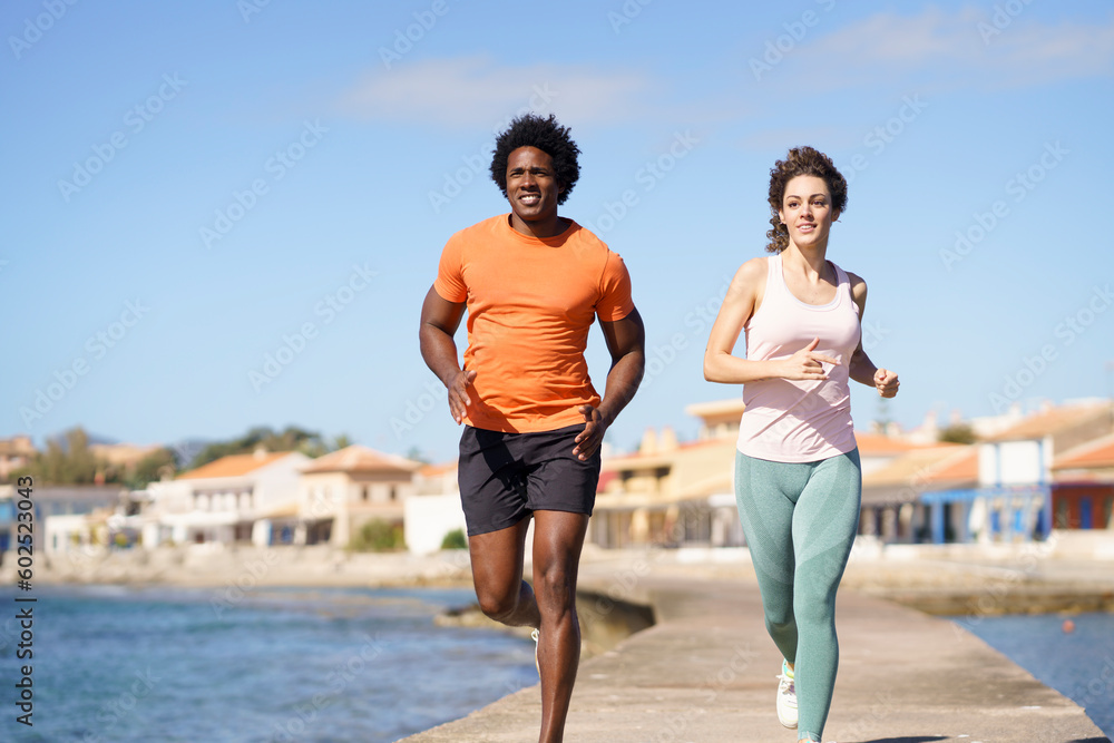 Couple doing running exercise on pier near sea in coastal area Couple doing running exercise on pier near sea in coastal area