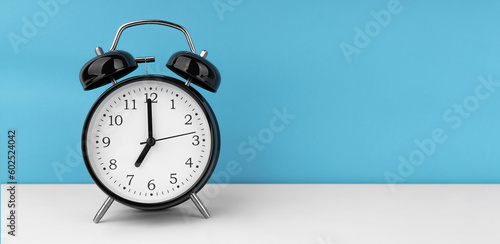 Black alarm clock on blue background