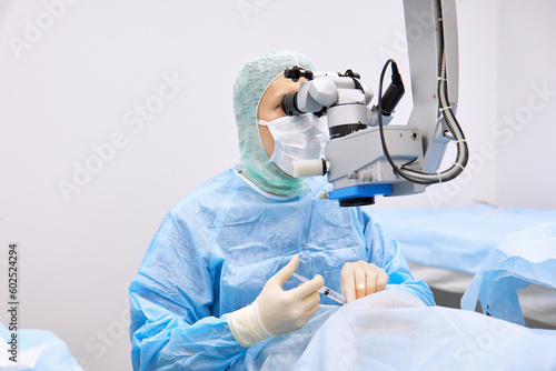 Surgeon performing eye surgery with microscope photo