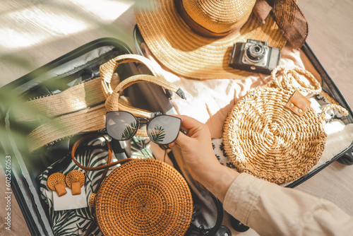 Woman hand holding sunglasses, hat, bag and other things on wooden table. Travel concept