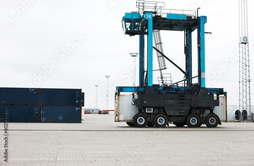 Shipping, cargo and logistics with straddle carrier for container, delivery and transportation at port. Freight, export and global stock with loading vehicle for economy, storage and industrial photo