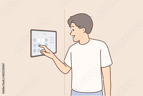 Man controls smart home system using digital panel hanging on wall to turn iot devices on and off