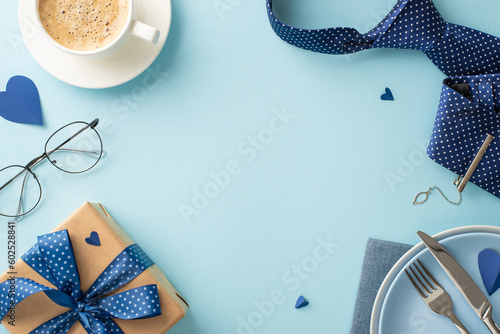 Plan an eye-catching Father's Day table setting with a flat lay top view coffee, dishes, cutlery, tie, hearts, accessories, spectacles, giftbox on a pastel blue background and an empty frame for text