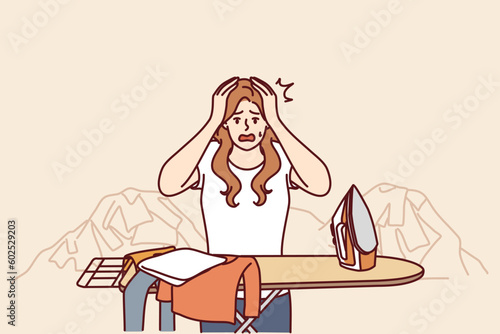 Housewife woman ironing clothes and clutching head in panic due to overload and fatigue. Housewife with iron stands near pile of clothes and needs assistant to take care of household
