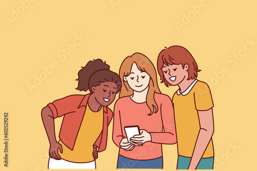 Teenage girls look at mobile phone and laugh at interesting video found on internet. Happy school age girls with smart phone are passionate about app and online games allowing to have fun